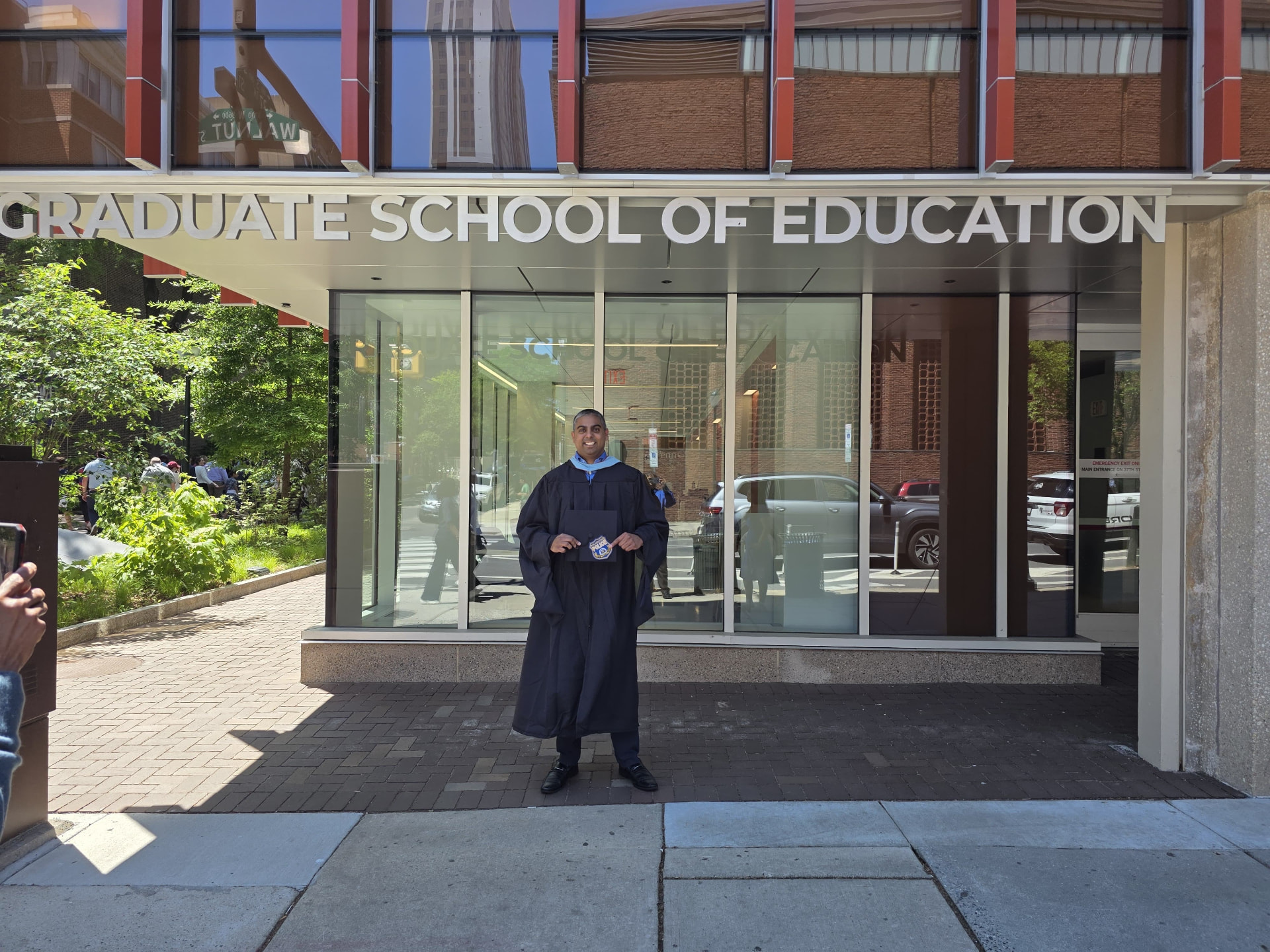 Philip Singh in graduation regalia outside the University of Pennsylvania Graduate School of Education
